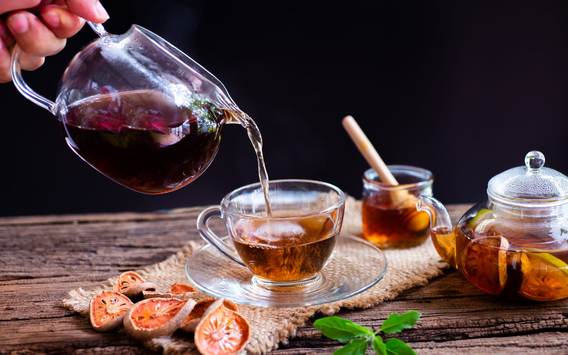 Tea poured from glass teapot with honey.