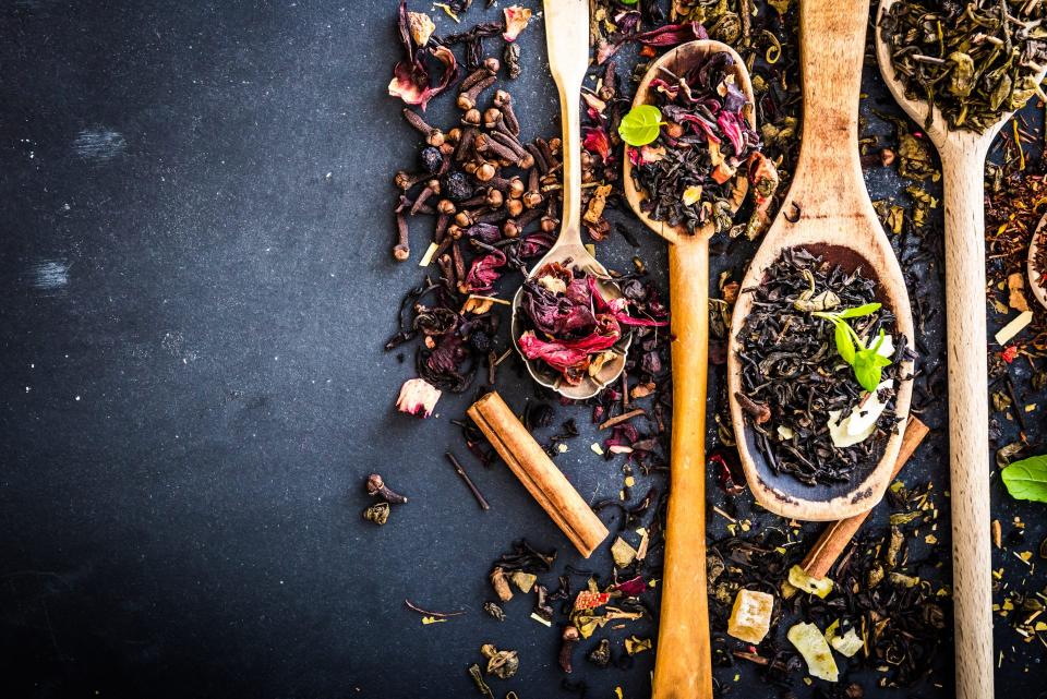 Wooden spoons holding different dry tea leaves.