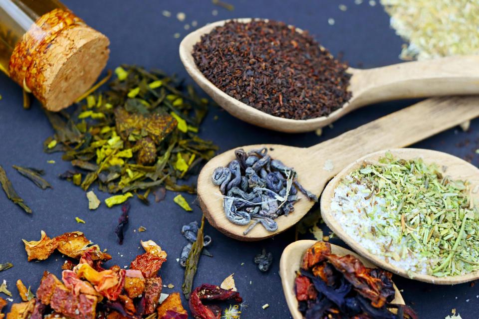 Various loose teas on wooden spoons.
