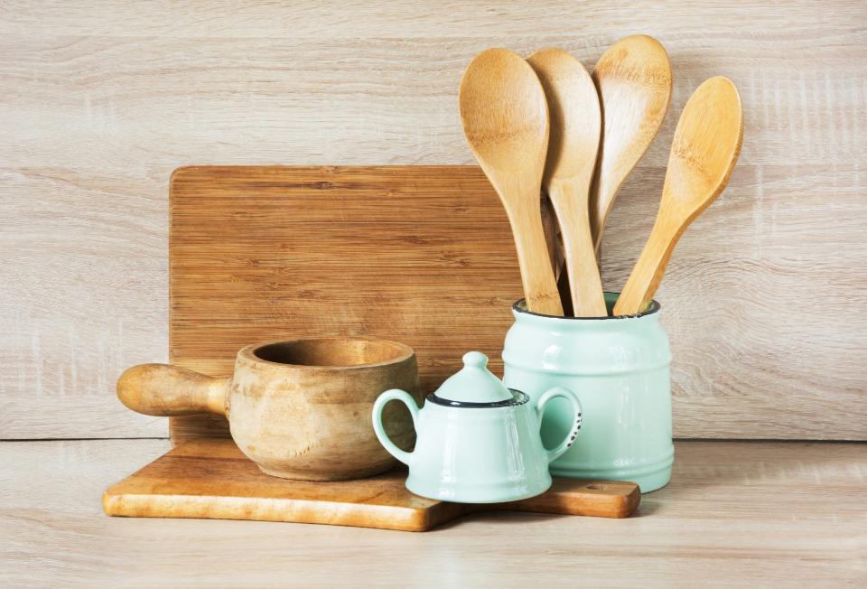 Wooden kitchen tools beside ceramic teapot.